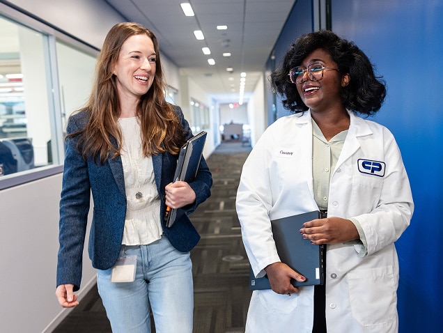 Two scientists smiling and talking in a corridor